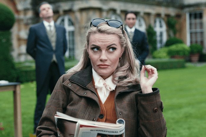 Chanel Cresswell as Tammy Horniman, sat on a chair, with a magazine in her hands